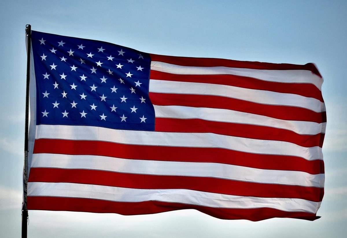 A U.S. flag waves in the breeze. The image is courtesy of Unsplash.