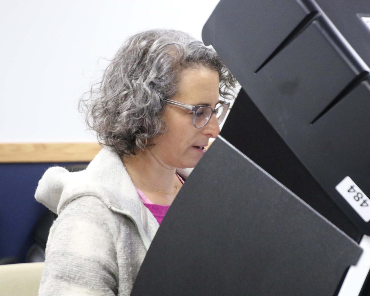 A woman looks down at the screen in a voting machine as she is casting her vote during early voting at the Benton County Administration Building on Feb. 17.