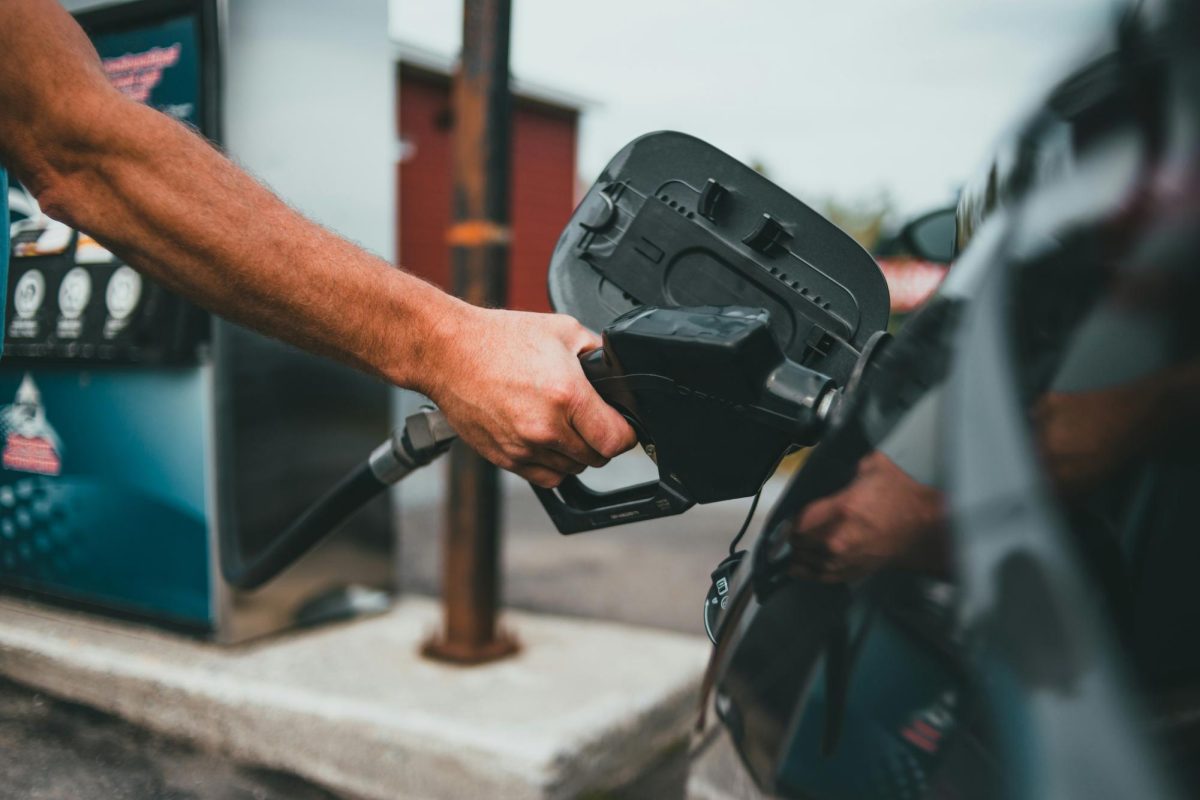A hand holds onto the gas pump nozzle as the person prepares to pump gasoline into a car's fuel tank.