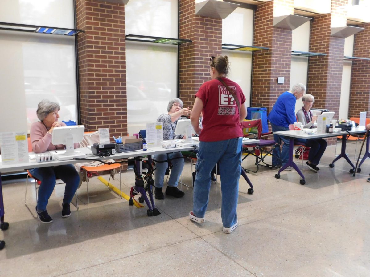 Several individuals seated at tables help a voter get checked in on the day of March 3 primaries.