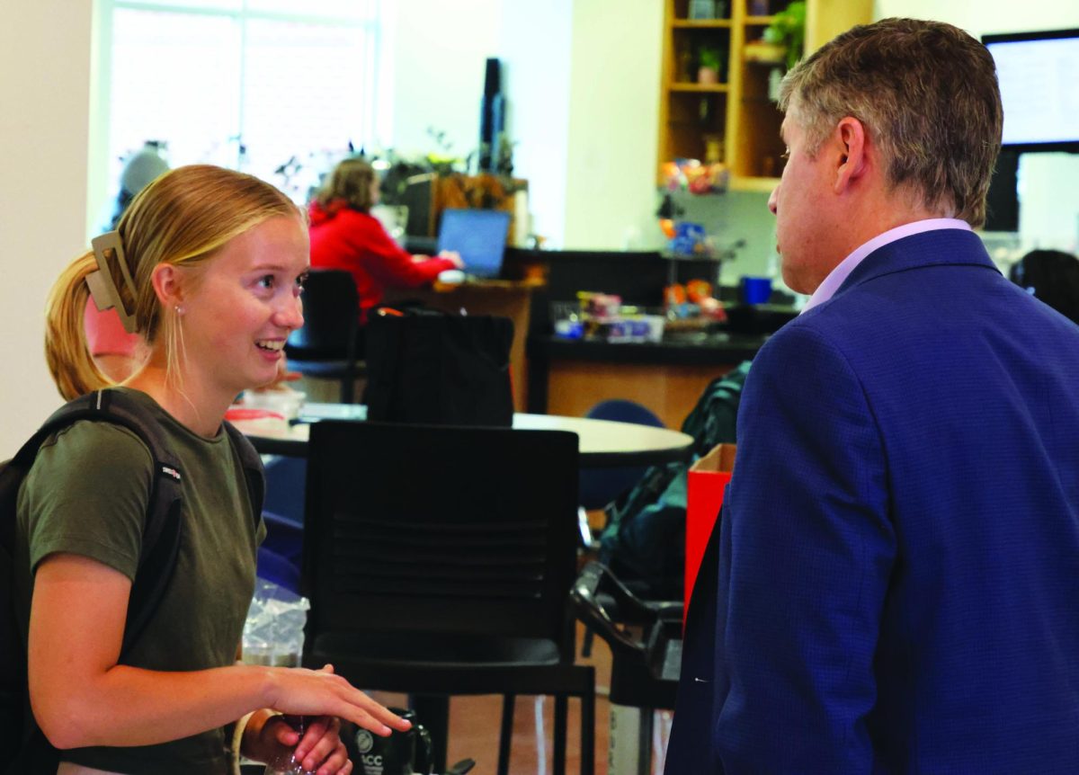 A student on the left looks toward NWACC President Dennis Rittle during the pastries event at the student center.